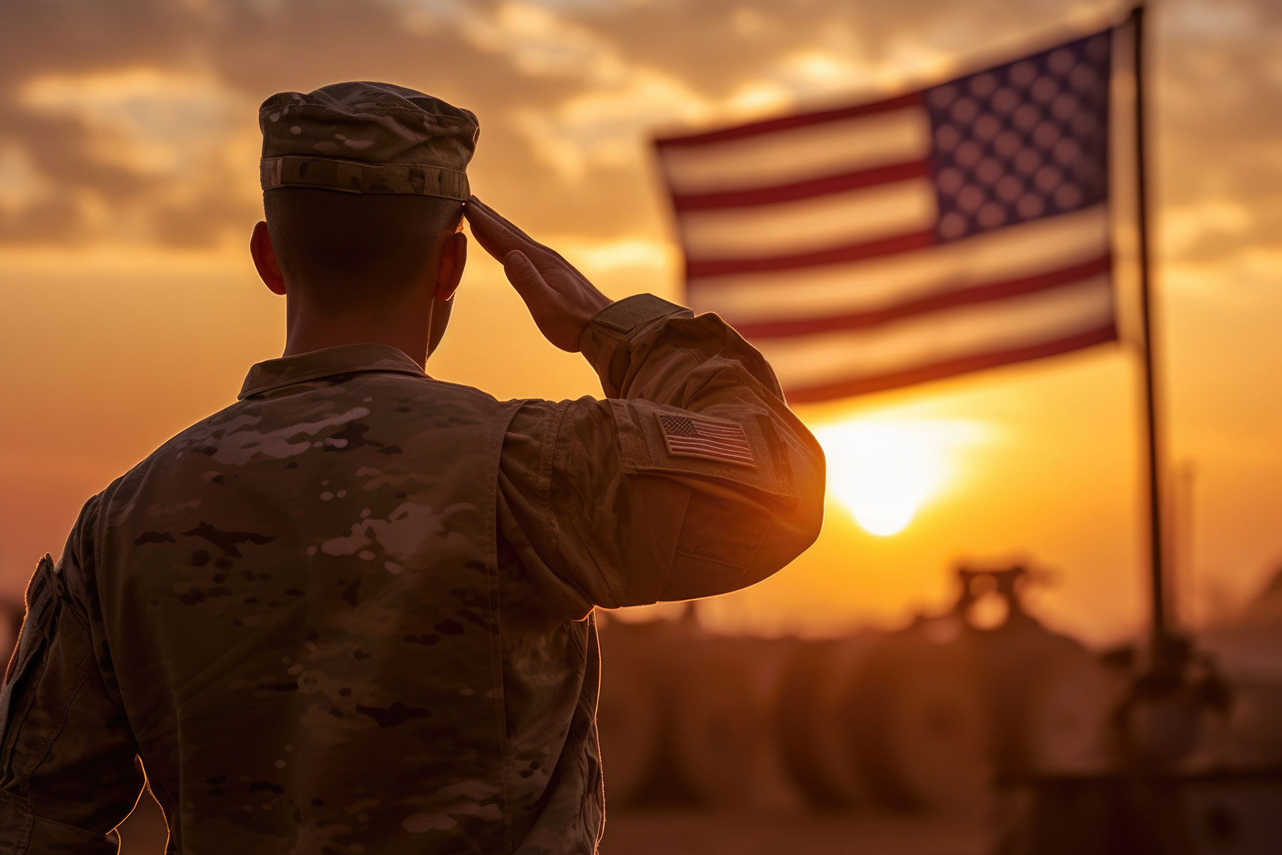veteran saluting the American flag while the sun sets in the background.