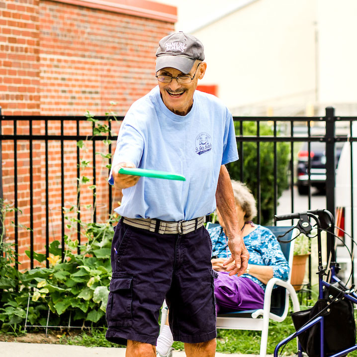 Adult Day client, Sam throwing a frisbee outdoors.