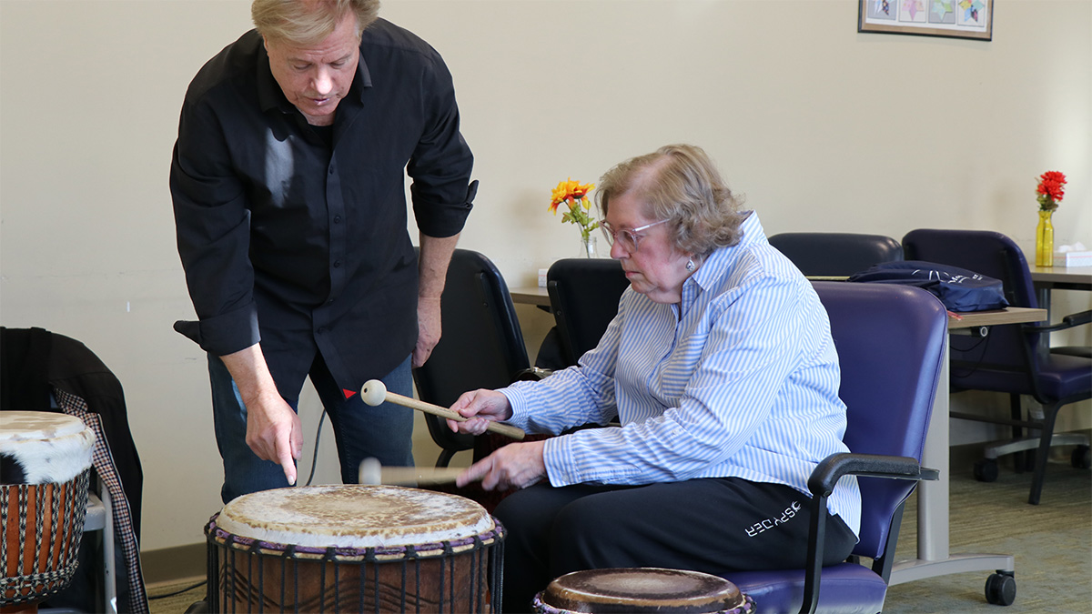 Randy Armstrong helps Donna, a participant in Easterseals NH’s Adult Day Program, learn a new drumming technique.