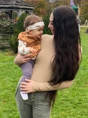 Kearstyn holding her child Armani outdoors.