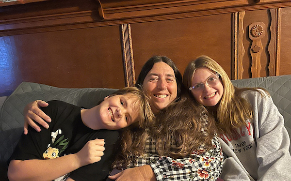 kendy sitting on a couch with two children either side. everyone is smiling.