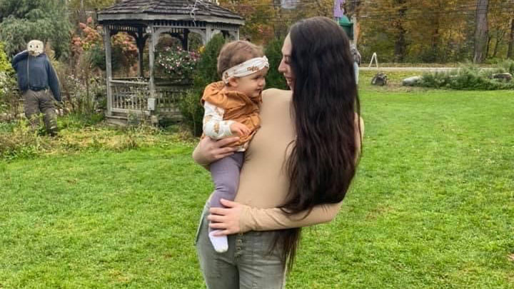 Kearstyn holding her daughter outdoors.