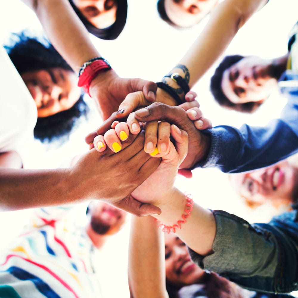 A group of kids with their hands in a circle.