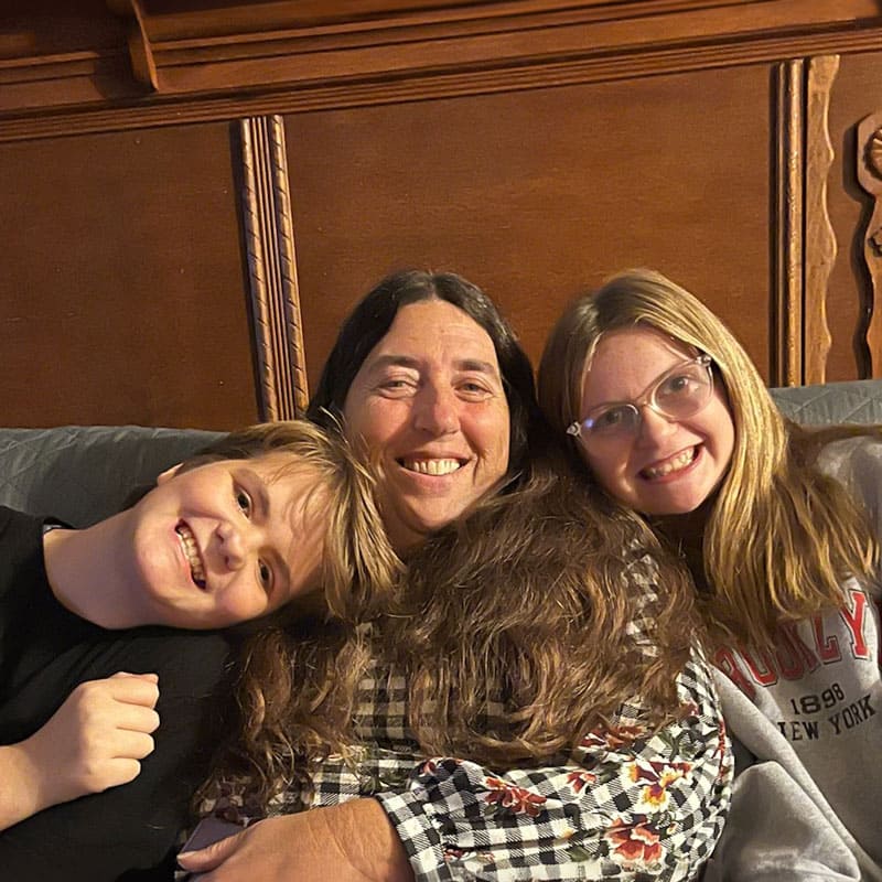 Kendy sitting on a couch with two children either side. everyone is smiling.